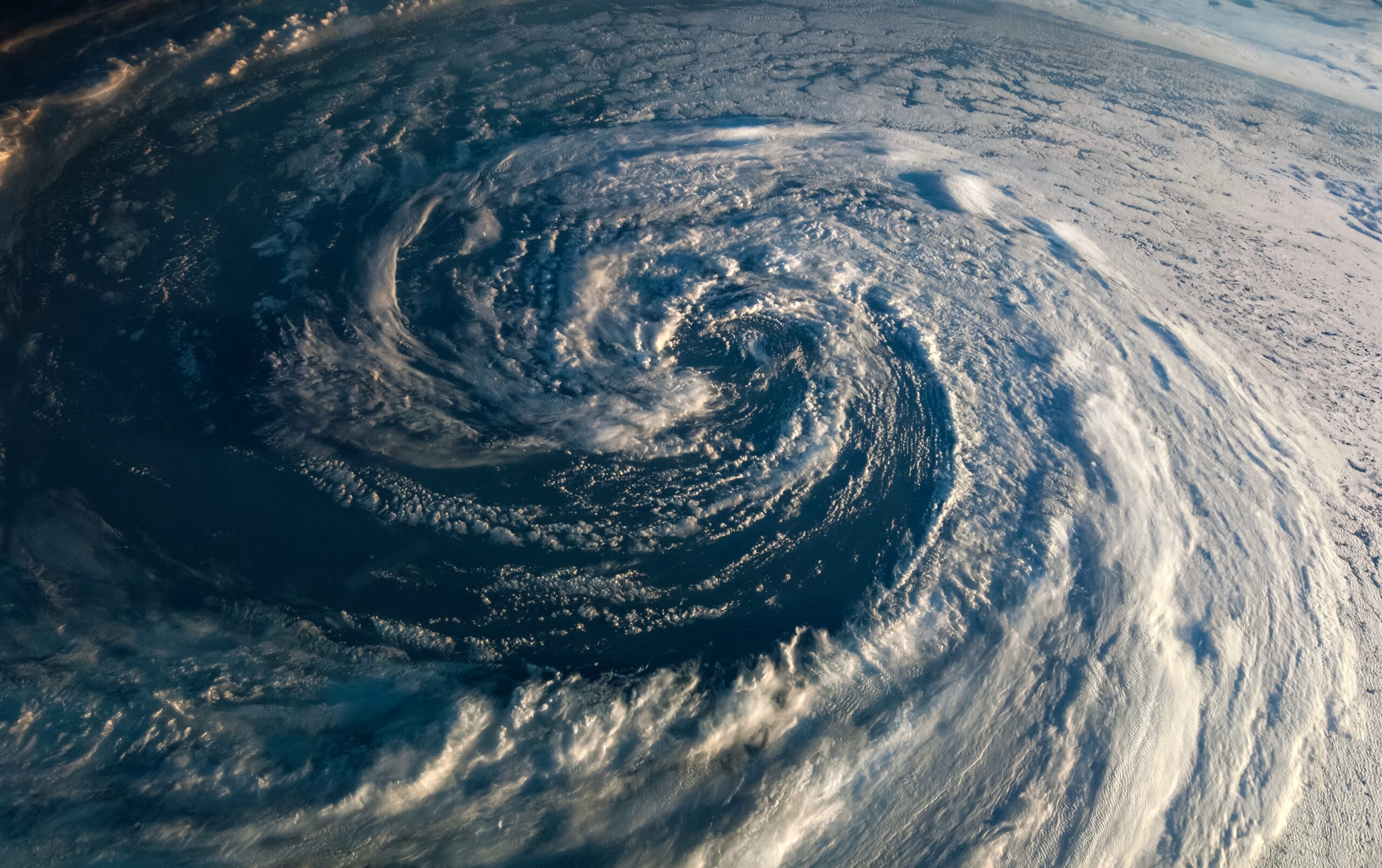 Satellite view of a powerful tropical cyclone over the ocean with a well-defined eye and spiraling cloud bands around it.
